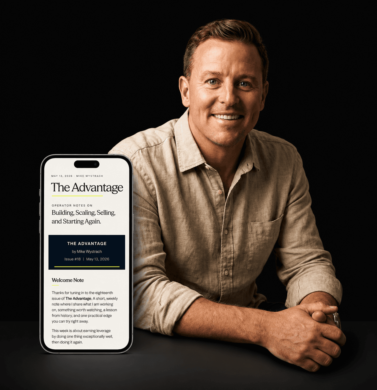 Mike Wystrach holding a phone showing The Advantage newsletter